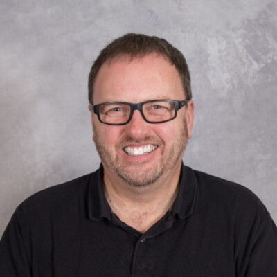 A man in glasses smiling for the camera, advocating for Beyond Instruction: Closing the Educational Gaps for Children with Autism.