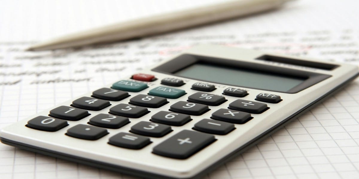 Close-up of a calculator on graph paper with handwritten notes, accompanied by a pen—a perfect setup for self-paced study.