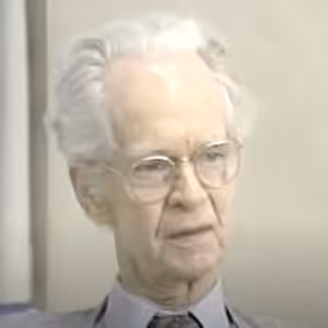 Elderly person with glasses and white hair.
