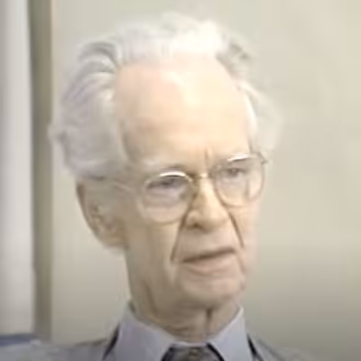 Elderly person with glasses and white hair.
