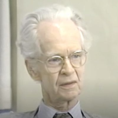 Elderly person with glasses and white hair.