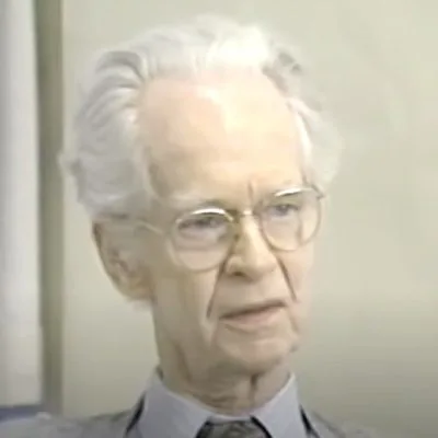 Elderly person with glasses and white hair.